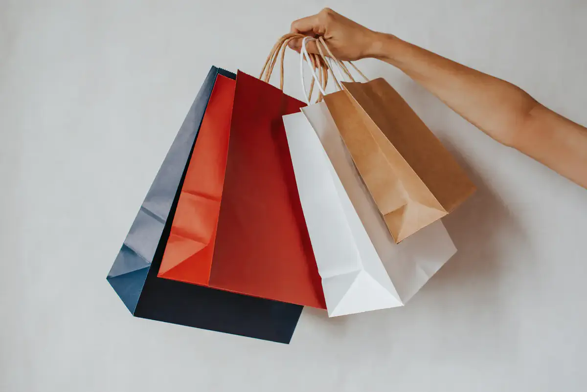 A hand holding plain shopping bags
